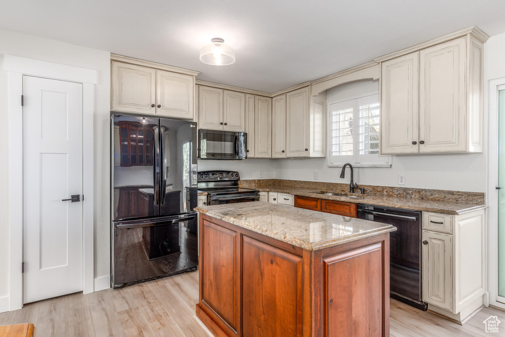 Kitchen with a center island, sink, light hardwood / wood-style floors, and black appliances