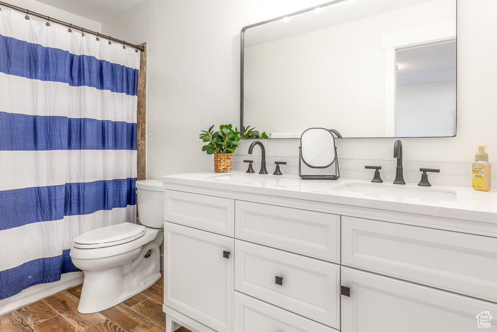 Bathroom with toilet, hardwood / wood-style floors, and double sink vanity
