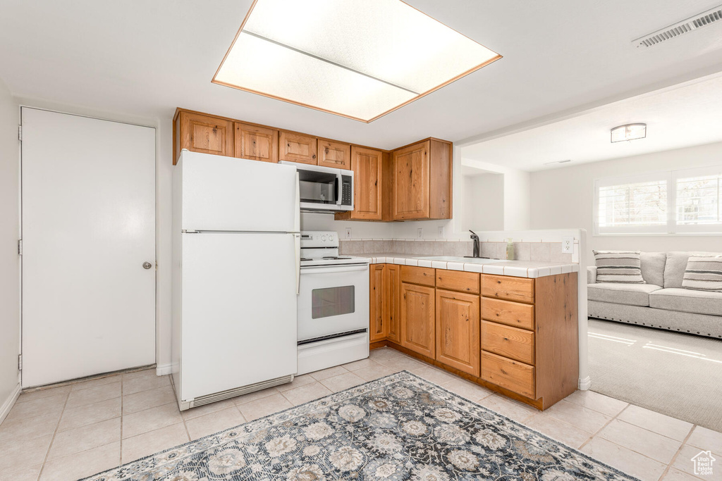 Kitchen featuring light carpet, white appliances, and sink