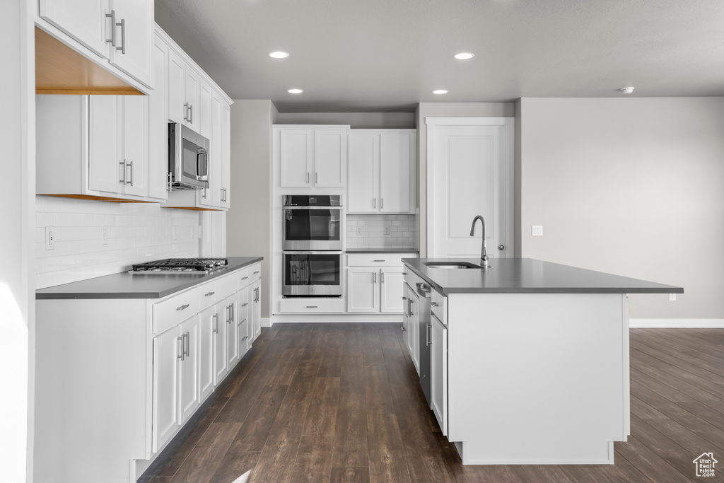 Kitchen featuring white cabinets, sink, backsplash, dark hardwood / wood-style flooring, and stainless steel appliances