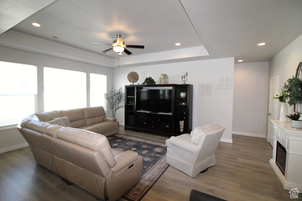 Living room with ceiling fan, hardwood / wood-style floors, and a raised ceiling
