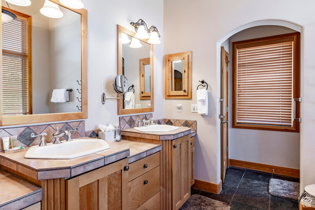 Bathroom featuring backsplash, tile flooring, and double sink vanity