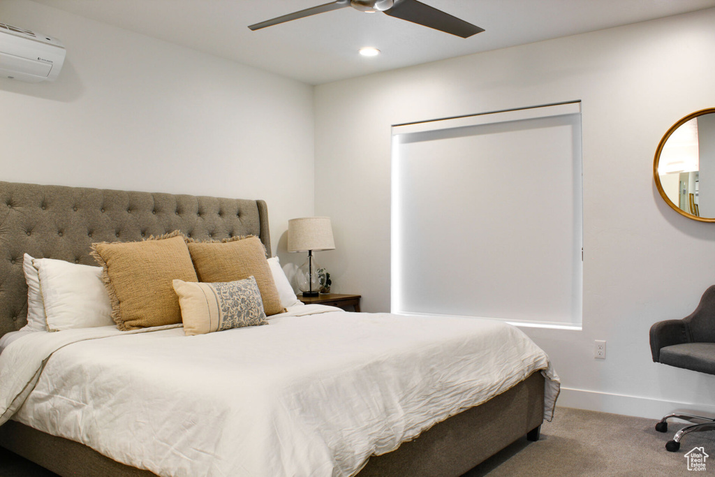 Bedroom featuring light colored carpet, ceiling fan, and an AC wall unit