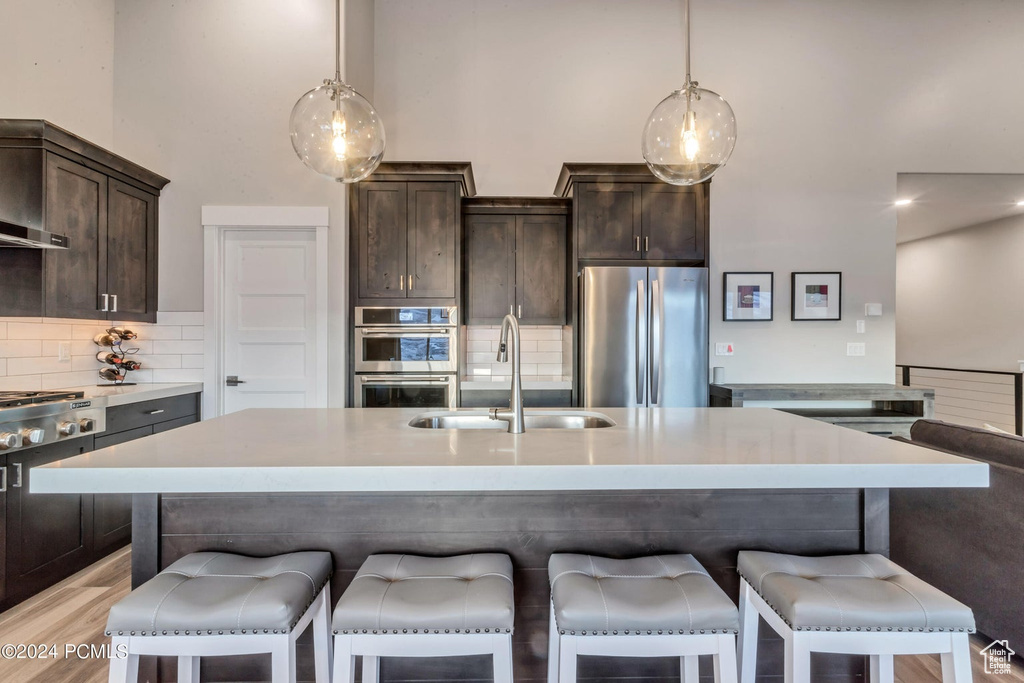 Kitchen featuring tasteful backsplash, stainless steel appliances, sink, and hanging light fixtures