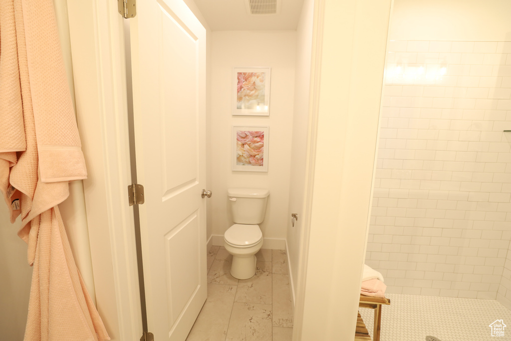 Bathroom featuring tile floors, a tile shower, and toilet