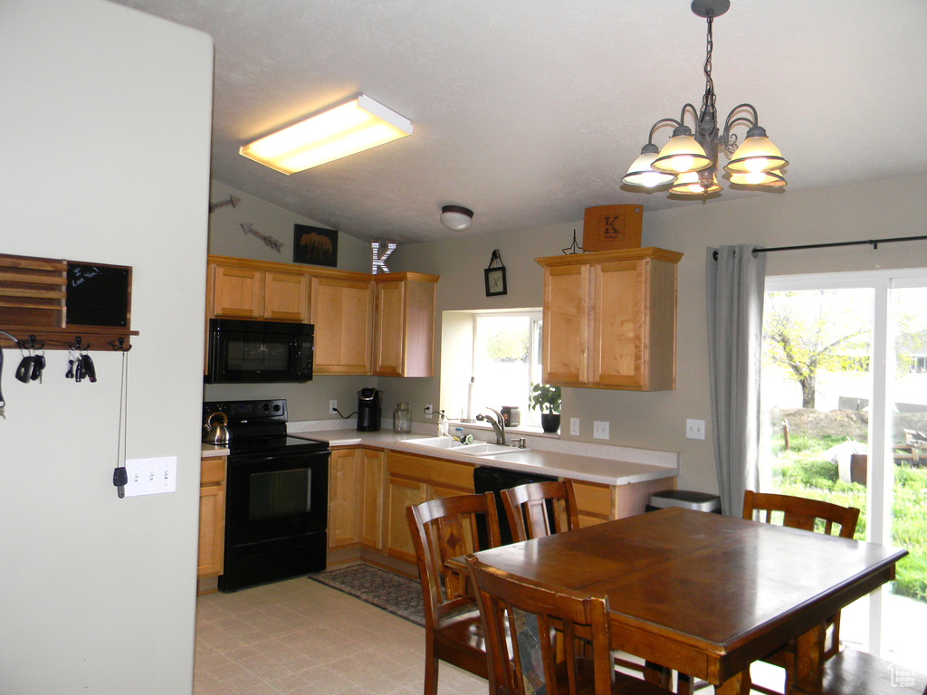 Kitchen with lofted ceiling, a wealth of natural light, light tile floors, and black appliances