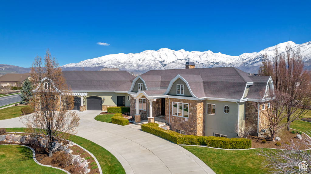 Ranch-style home featuring a mountain view, a front lawn, and a garage