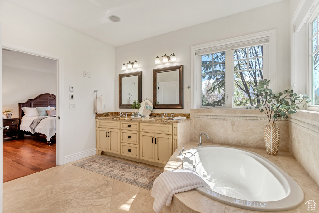 Bathroom with double vanity, a washtub, and hardwood / wood-style flooring