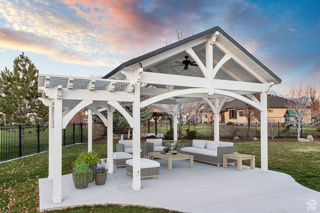 Patio terrace at dusk featuring ceiling fan, a yard, a pergola, and an outdoor hangout area