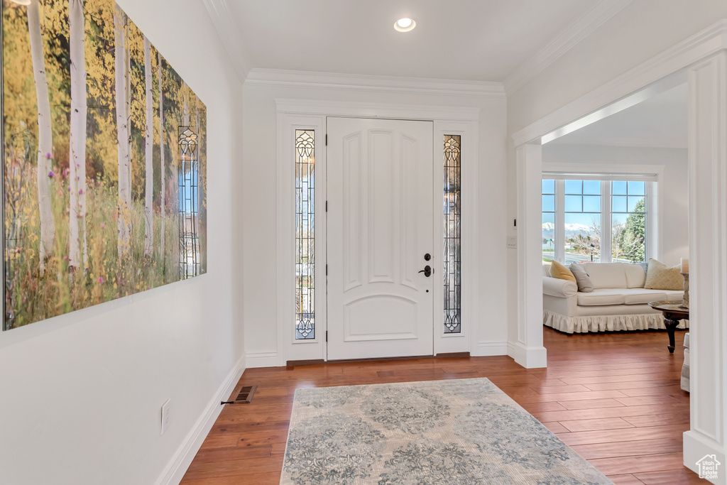 Foyer featuring crown molding and dark hardwood / wood-style flooring