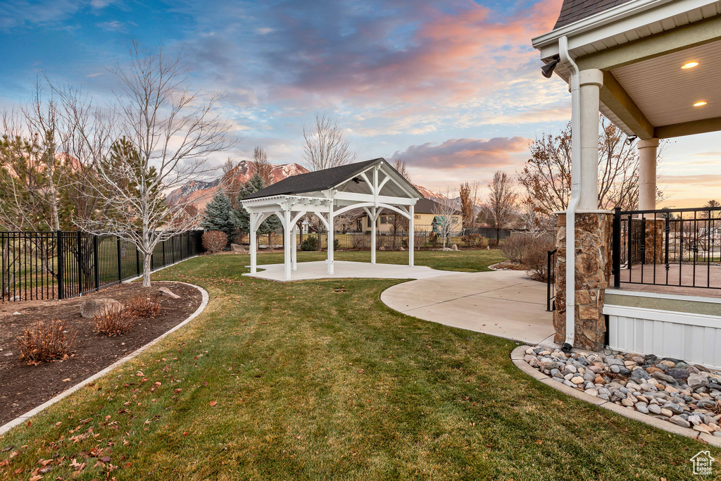 Yard at dusk with a patio area, a gazebo, and a mountain view
