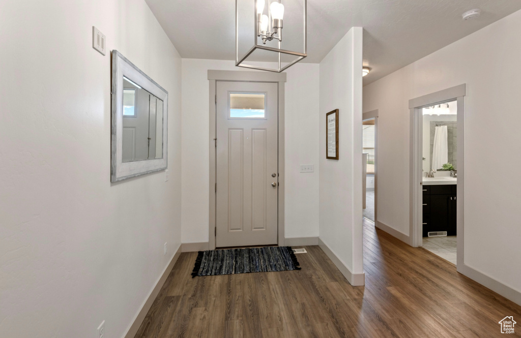 Foyer entrance featuring wood-type flooring, plenty of natural light, and a notable chandelier