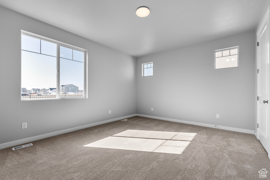 Empty room featuring plenty of natural light and light carpet