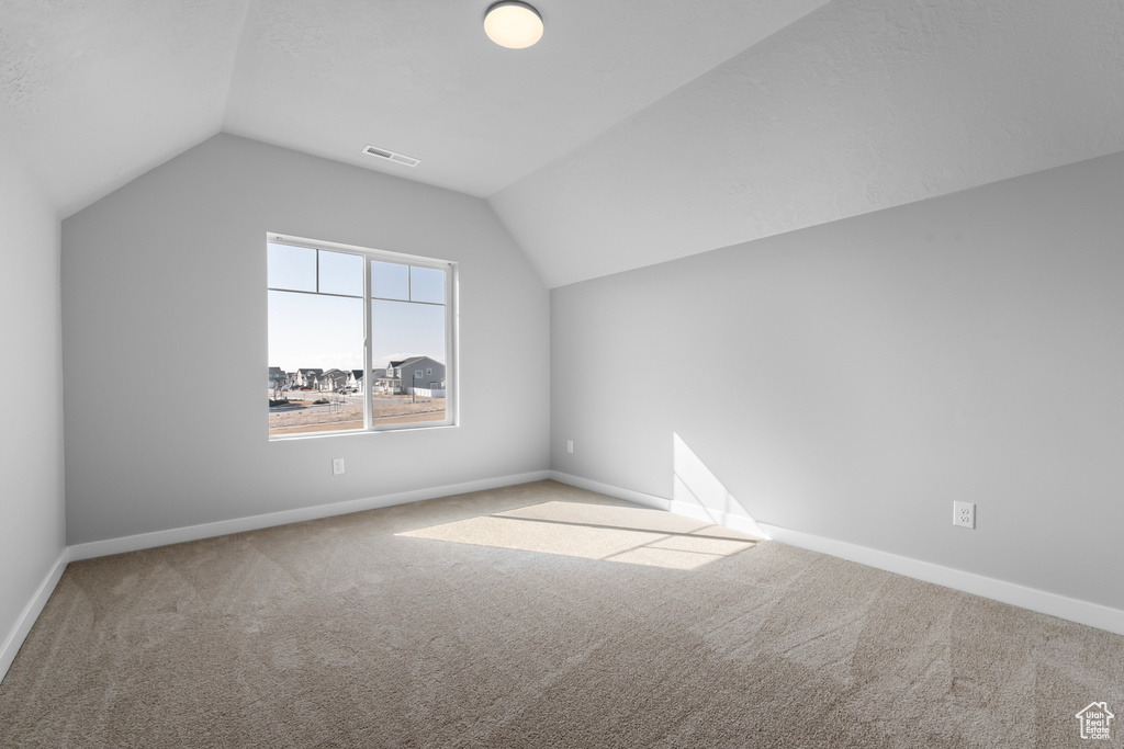 Additional living space with light colored carpet and lofted ceiling