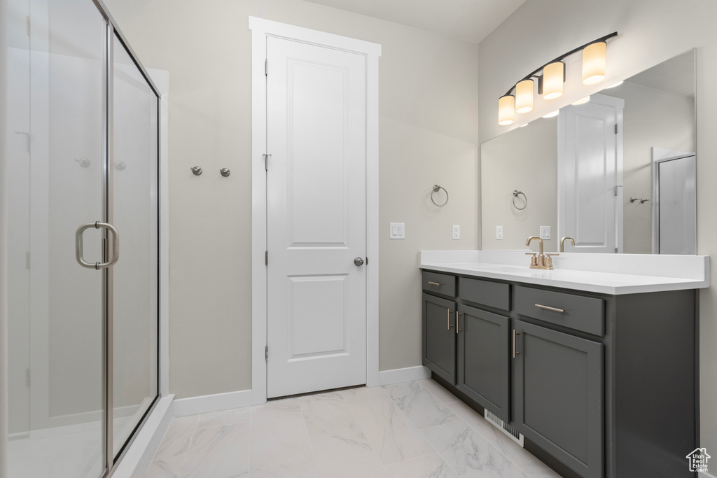 Bathroom featuring a shower with shower door, vanity, and tile flooring