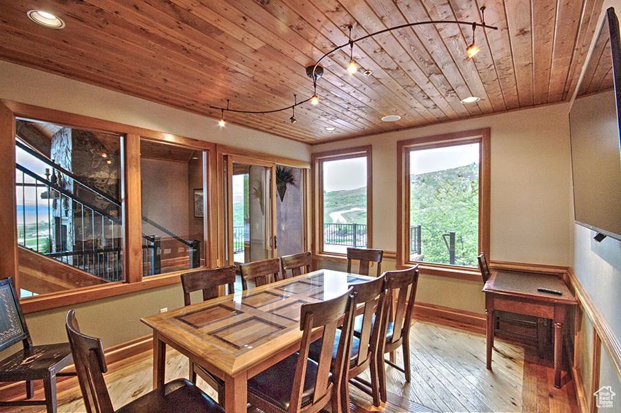 Dining room with light hardwood / wood-style flooring, rail lighting, and wood ceiling