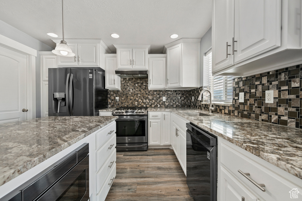Kitchen with pendant lighting, white cabinets, dark wood-type flooring, stainless steel appliances, and sink