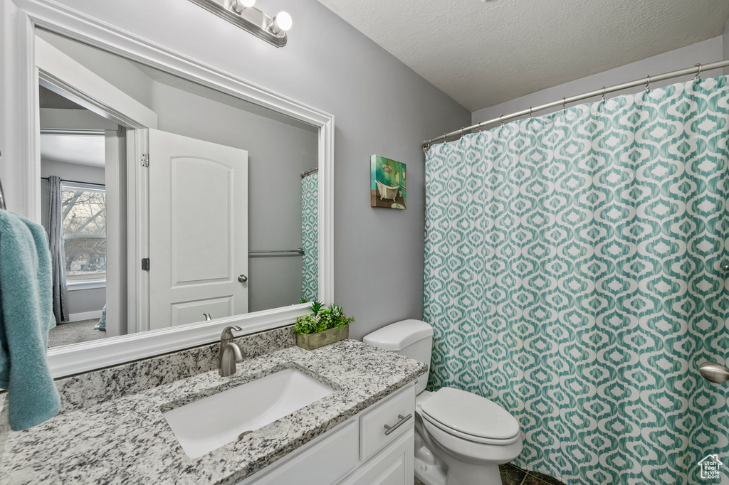 Bathroom featuring vanity, toilet, and a textured ceiling