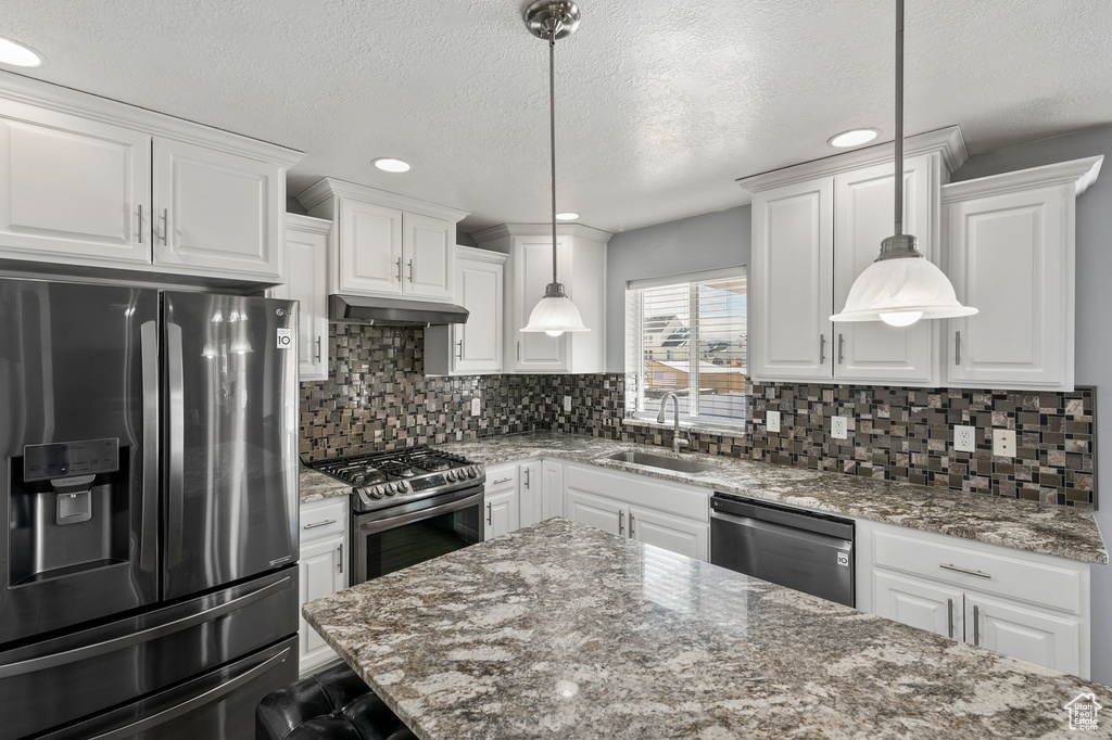 Kitchen with white cabinets, sink, backsplash, decorative light fixtures, and stainless steel appliances