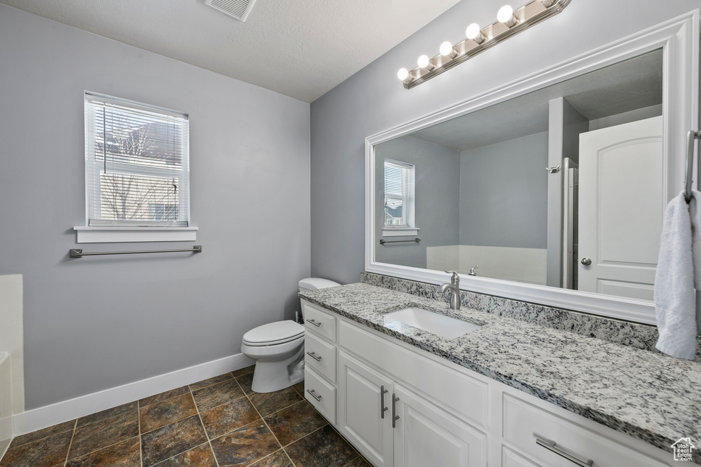 Bathroom with a healthy amount of sunlight, toilet, tile flooring, and vanity