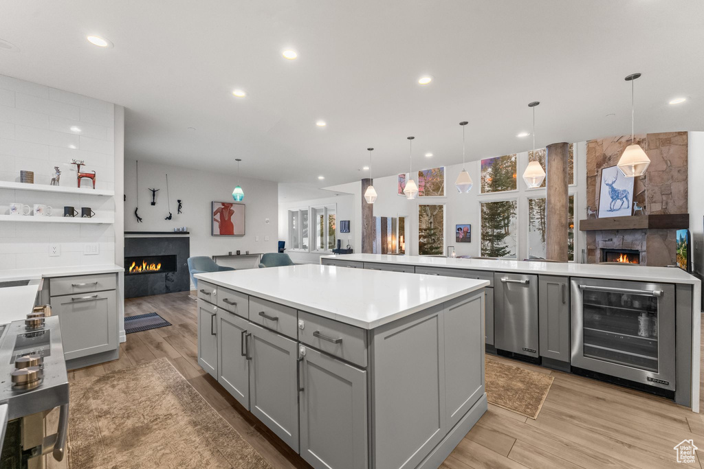 Kitchen featuring beverage cooler, hanging light fixtures, a center island, and a fireplace