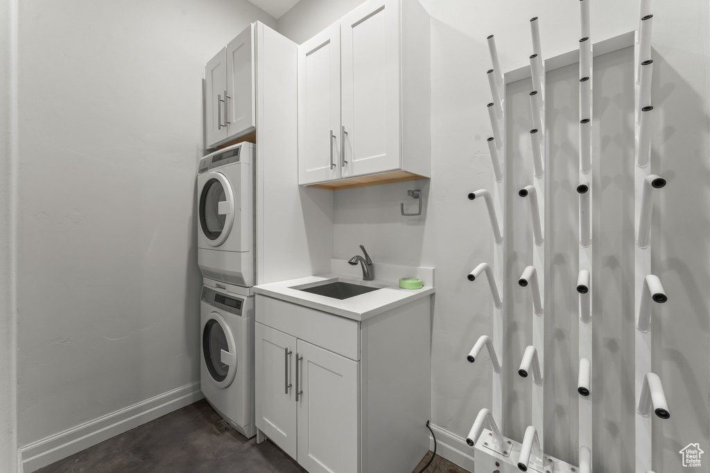 Washroom with stacked washing maching and dryer, cabinets, and sink