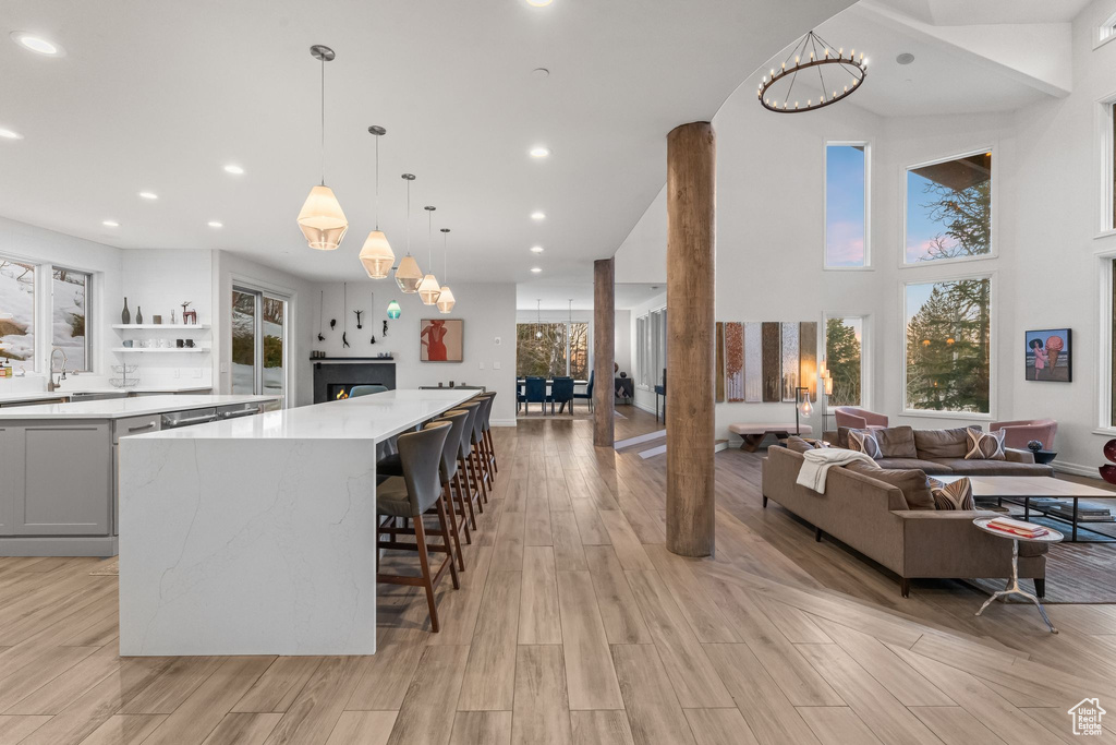Kitchen with hanging light fixtures, light hardwood / wood-style flooring, light stone counters, a kitchen breakfast bar, and an inviting chandelier