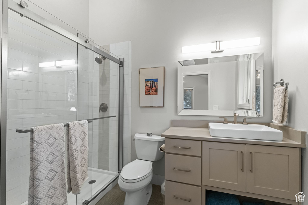 Bathroom with vanity with extensive cabinet space, an enclosed shower, and toilet
