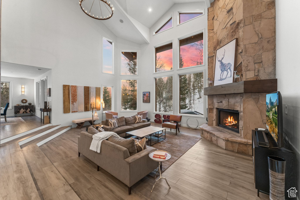 Living room featuring high vaulted ceiling, light hardwood / wood-style floors, and a stone fireplace
