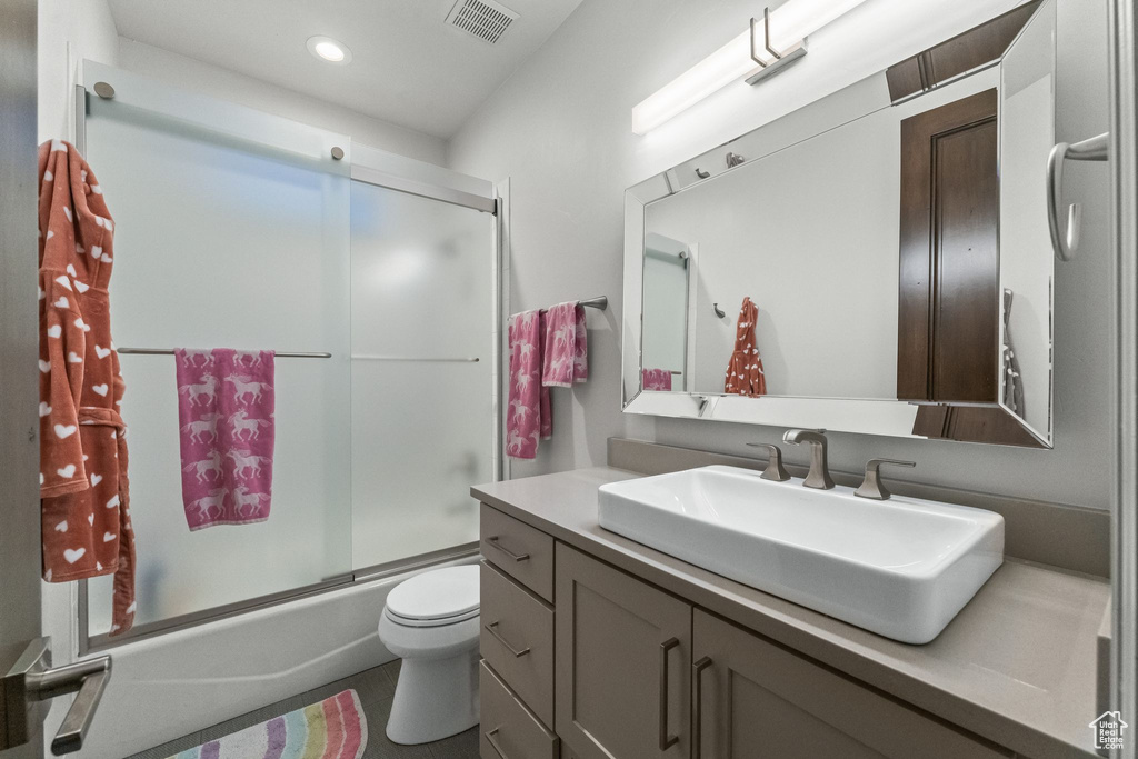 Full bathroom featuring vanity, toilet, and shower / bath combination with glass door