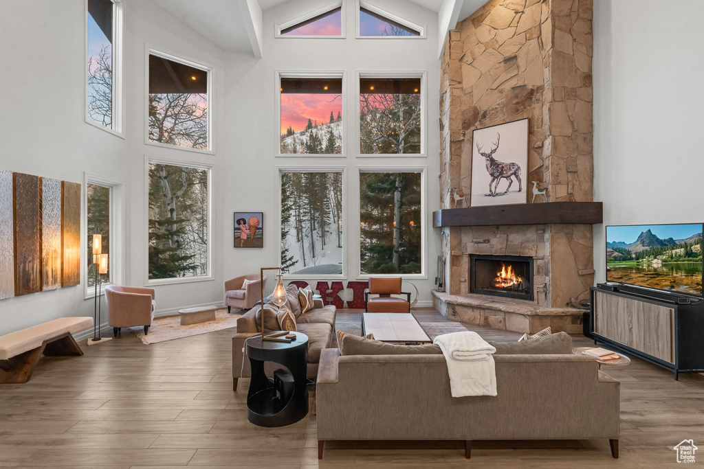 Living room with a fireplace, high vaulted ceiling, and light wood-type flooring
