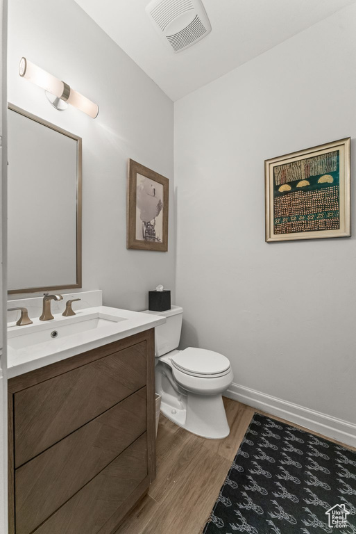 Bathroom featuring toilet, oversized vanity, and hardwood / wood-style floors