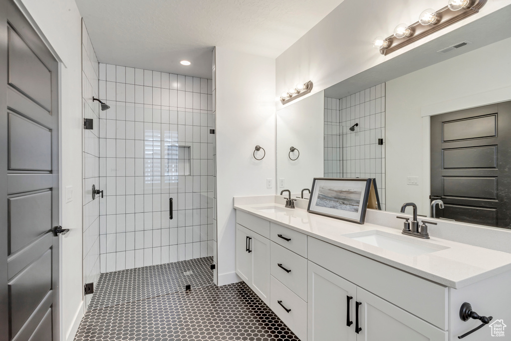 Bathroom featuring double sink, tile flooring, a tile shower, and large vanity