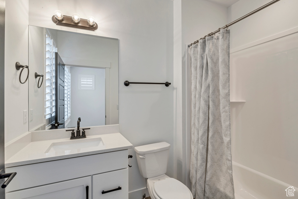 Full bathroom with vanity, shower / bathtub combination with curtain, and toilet