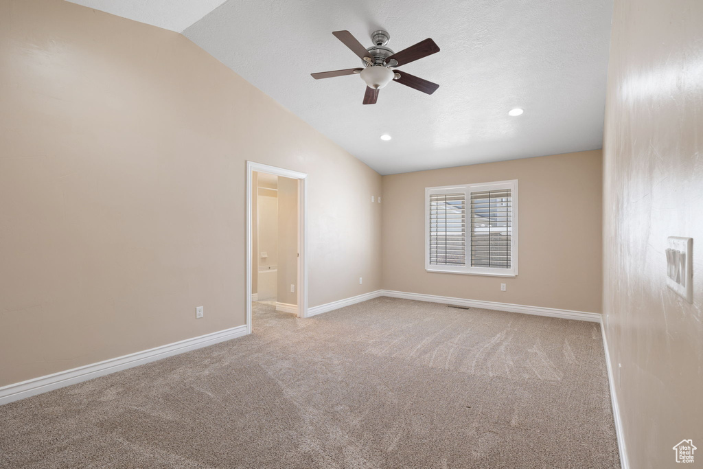 Carpeted spare room featuring ceiling fan and lofted ceiling