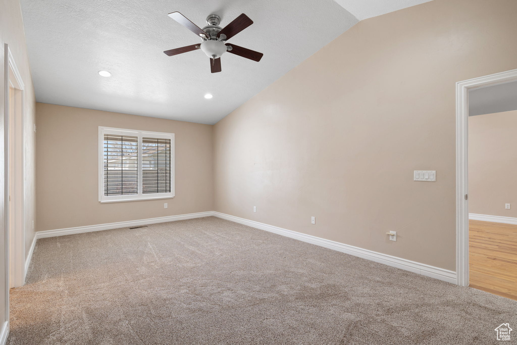 Empty room with ceiling fan, light wood-type flooring, and lofted ceiling