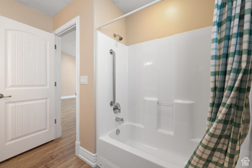 Bathroom with hardwood / wood-style flooring and shower / tub combo with curtain