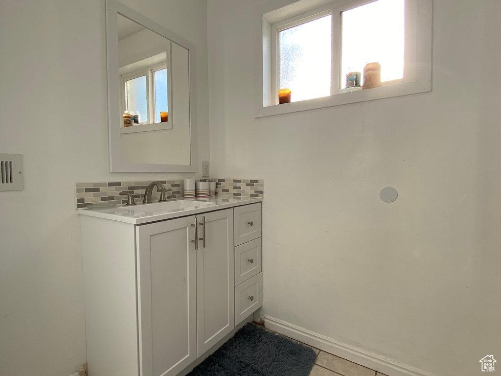 Bathroom with backsplash, vanity, tile floors, and a healthy amount of sunlight