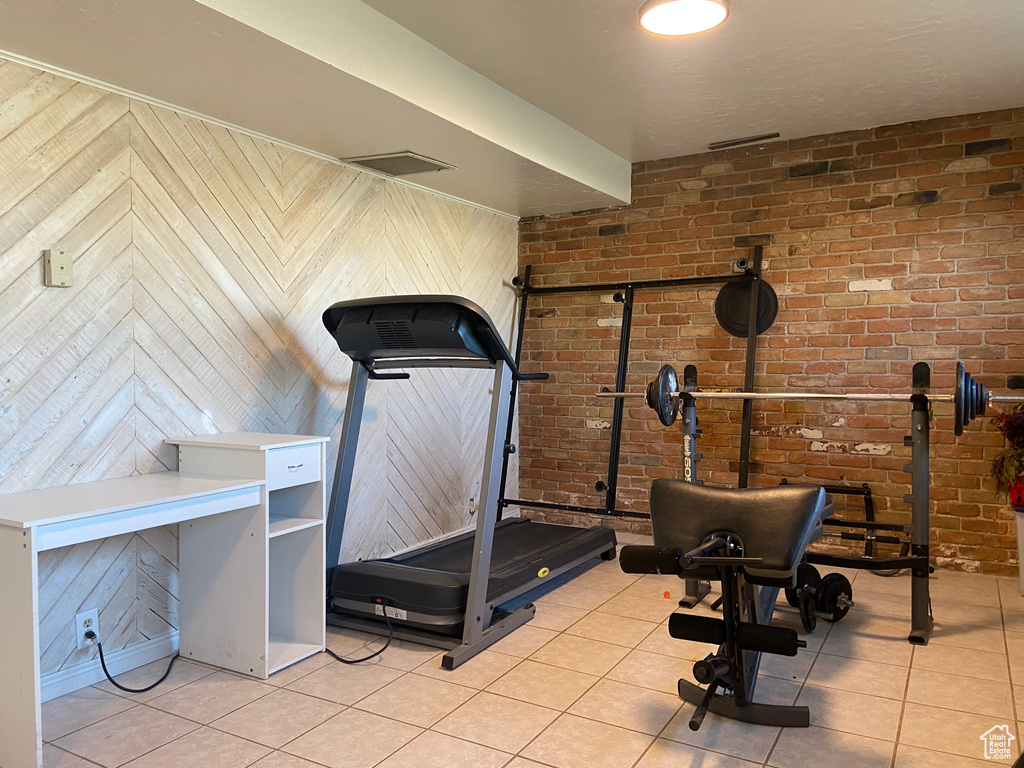 Exercise area featuring brick wall and light tile flooring