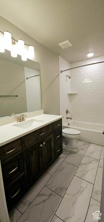 Full bathroom with tiled shower / bath combo, large vanity, tile floors, and toilet