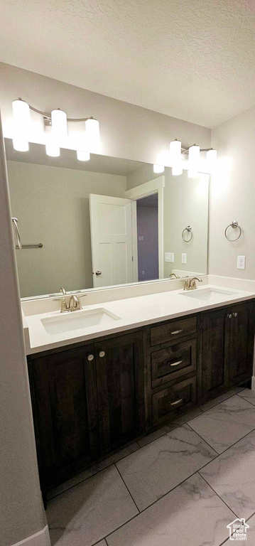 Bathroom with tile flooring, a textured ceiling, and double sink vanity