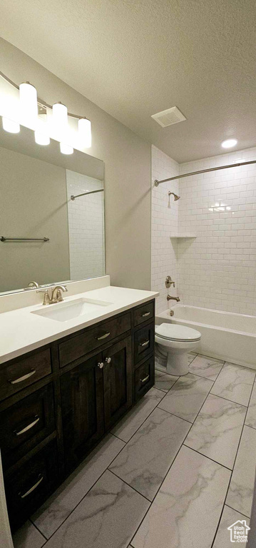 Full bathroom featuring vanity with extensive cabinet space, tiled shower / bath, toilet, and tile floors