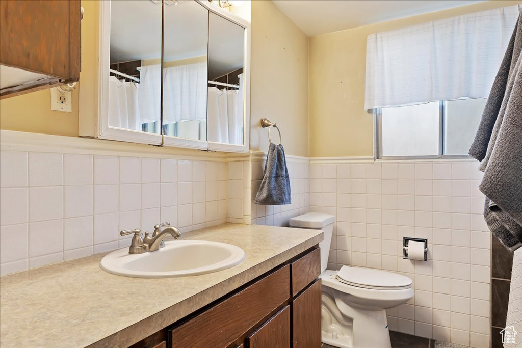 Bathroom featuring oversized vanity, backsplash, toilet, and tile walls