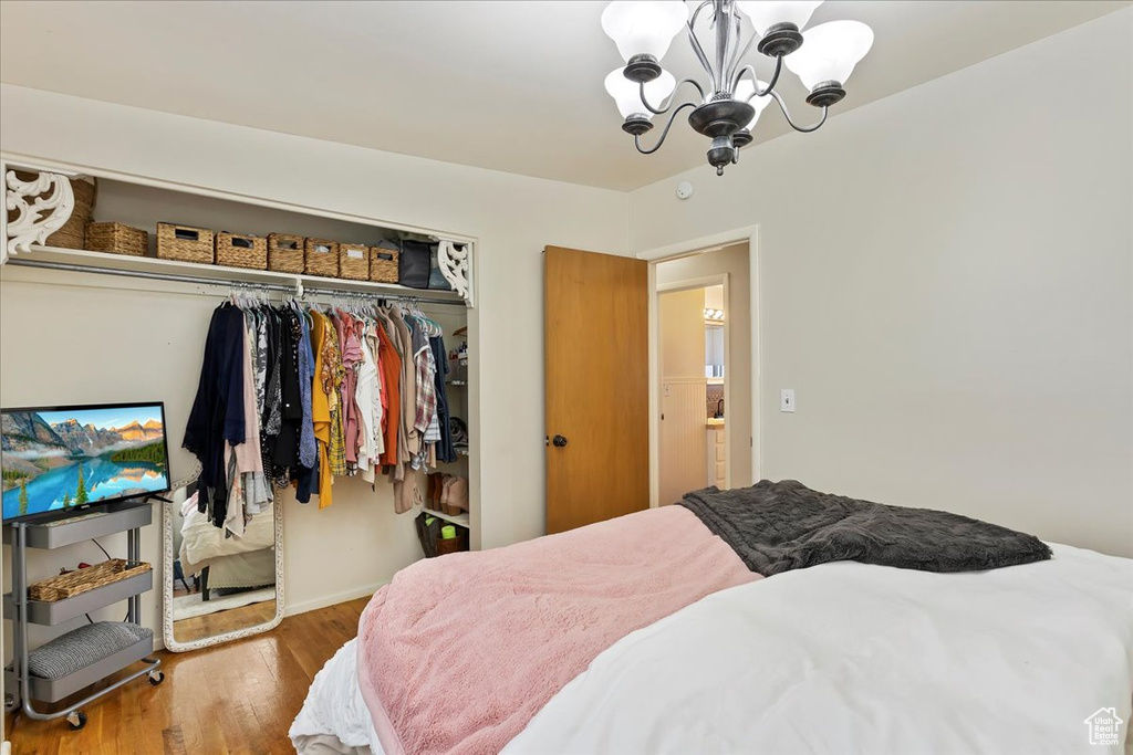 Bedroom with wood-type flooring, a closet, and a notable chandelier