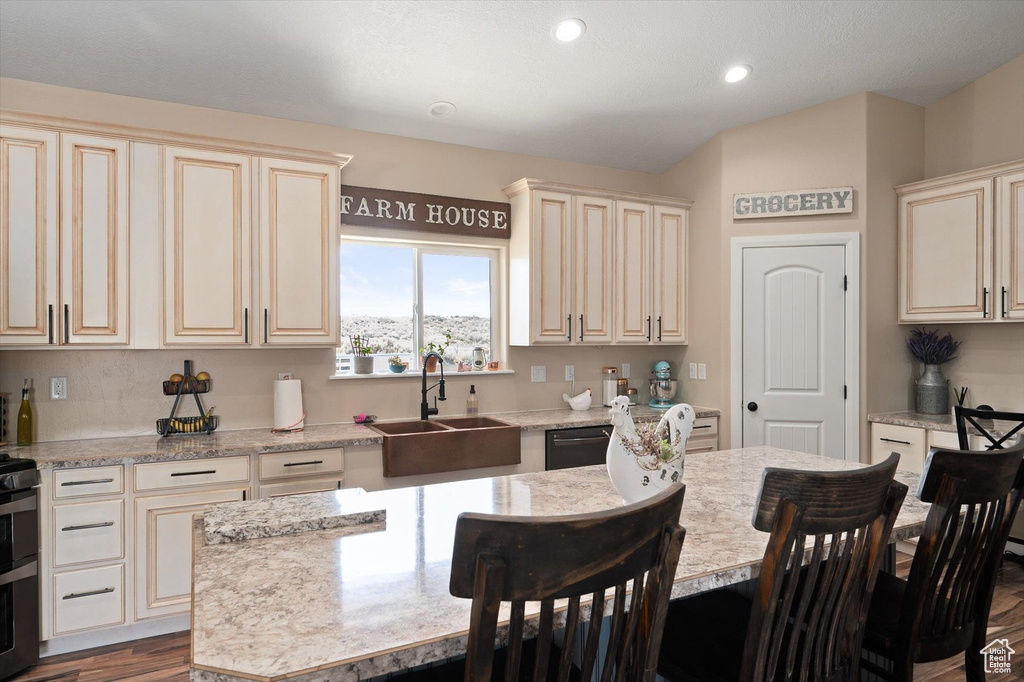 Kitchen featuring cream cabinets, a center island, a breakfast bar, and light stone counters