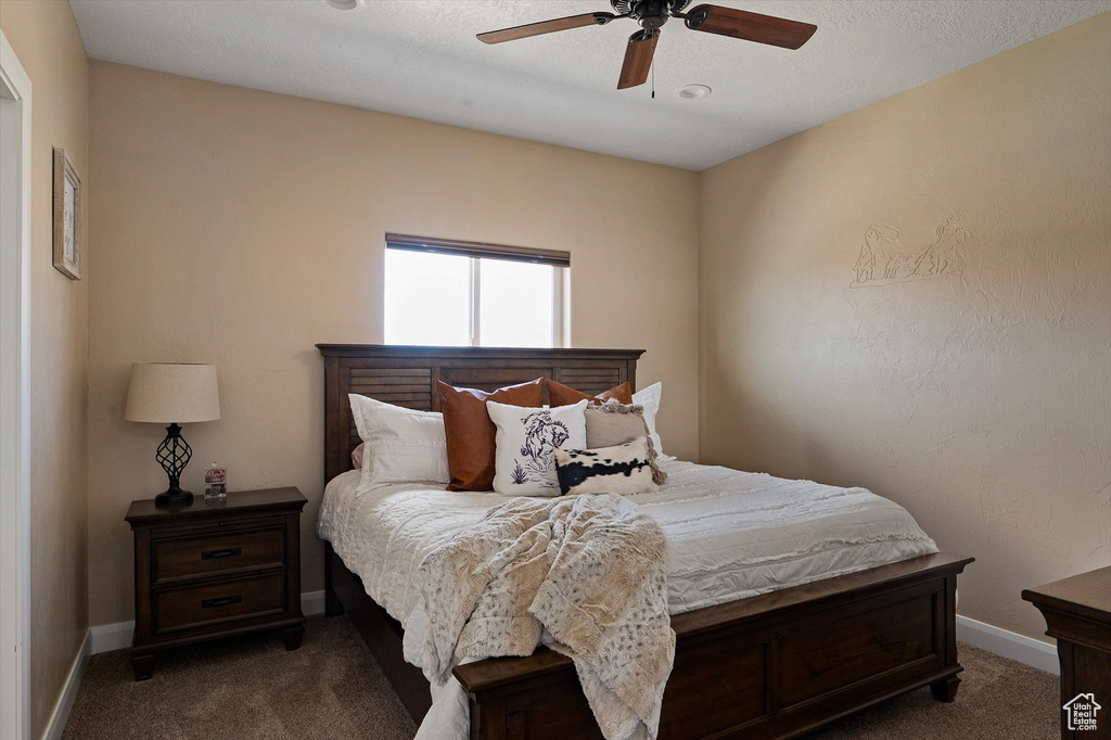 Bedroom with ceiling fan and dark carpet
