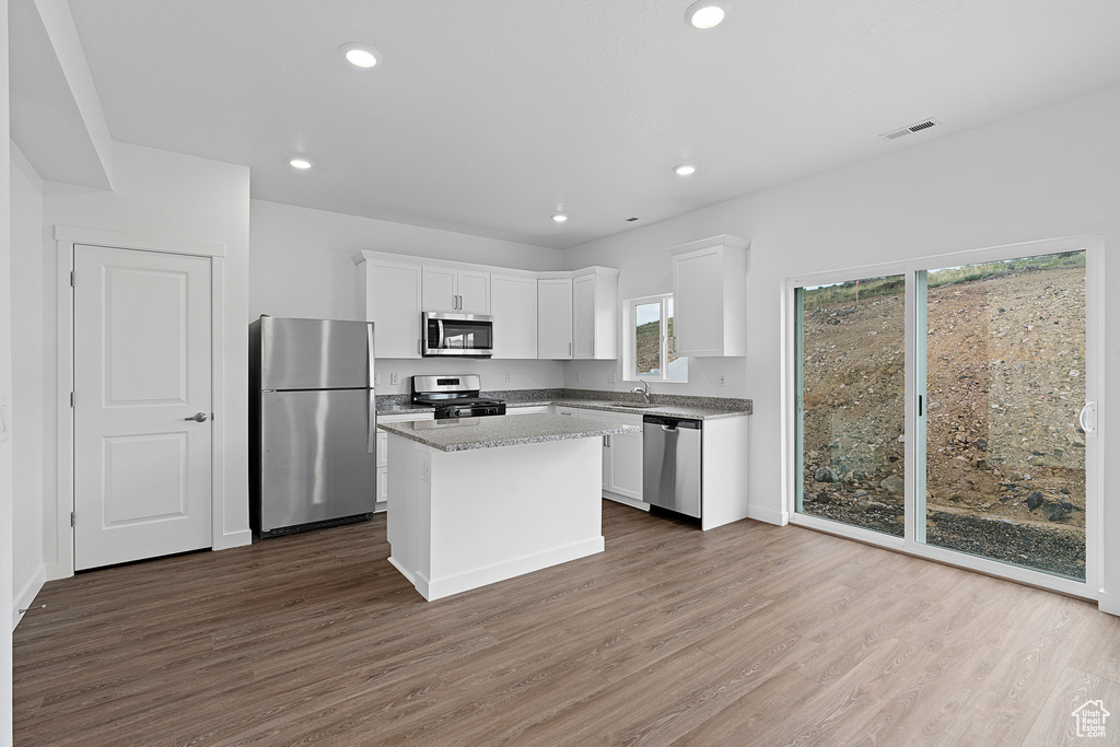 Kitchen with appliances with stainless steel finishes, dark hardwood / wood-style floors, a center island, and white cabinetry