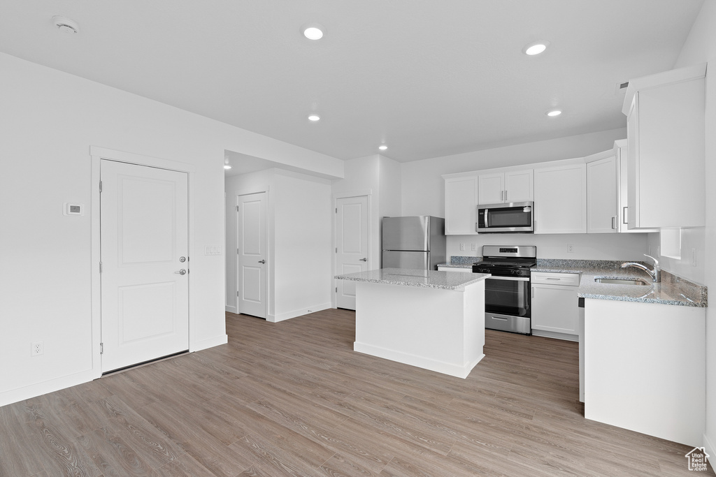 Kitchen featuring light hardwood / wood-style floors, appliances with stainless steel finishes, a center island, and white cabinetry