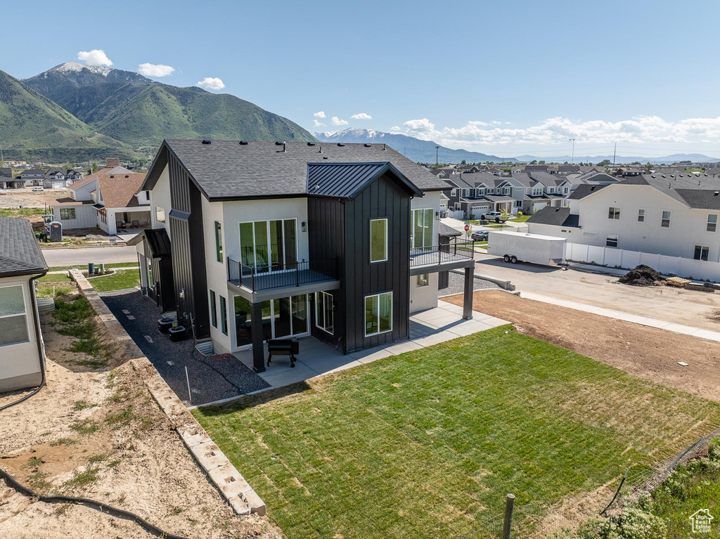 Rear view of property featuring a patio area, a mountain view, and a lawn