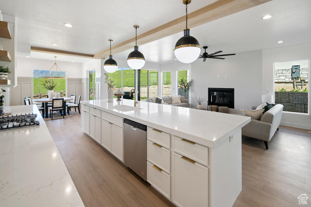 Kitchen featuring appliances with stainless steel finishes, white cabinetry, light wood-type flooring, and pendant lighting